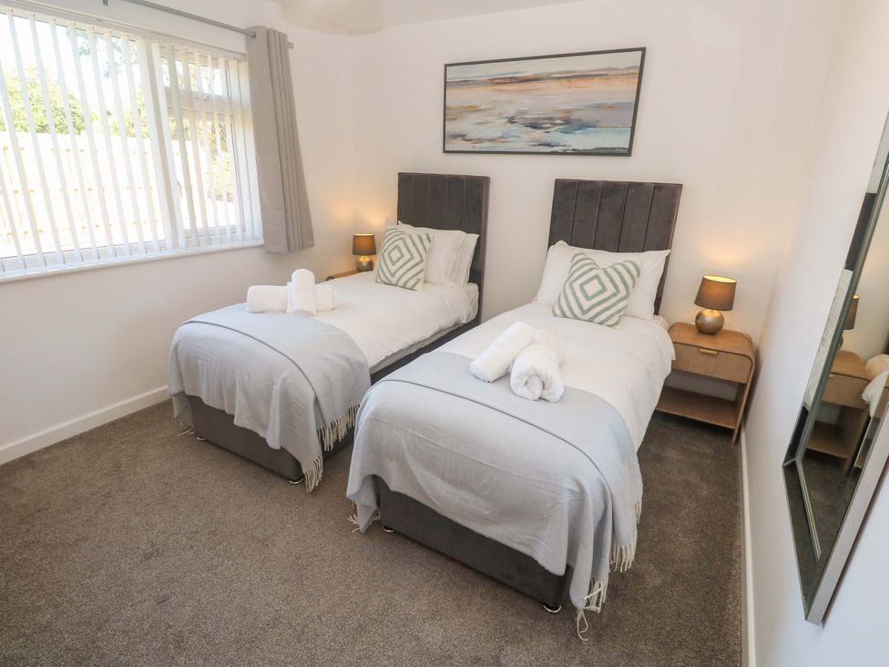 A bedroom with twin beds and a bedside table at Agan Paradhis in Quintrell Downs
