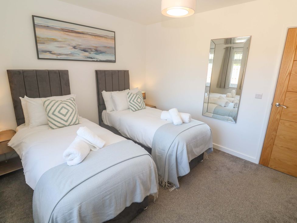 A bedroom with two single beds and a mirror at Agan Paradhis in Quintrell Downs