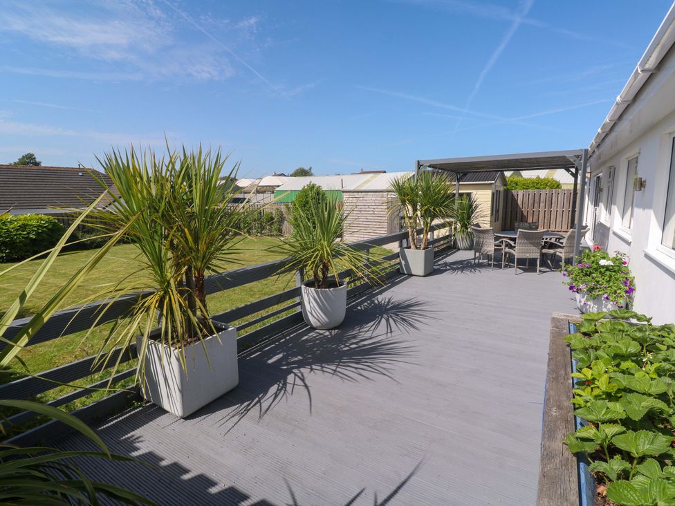 A deck with chairs and table surrounded by planters at Agan Paradhis in Quintrell Downs