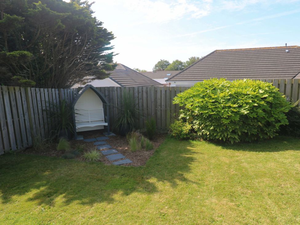 A garden with a bench and bush at Agan Paradhis in Quintrell Downs