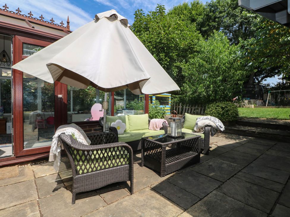 A garden area with seating and an umbrella at Taliesin in Hailsham