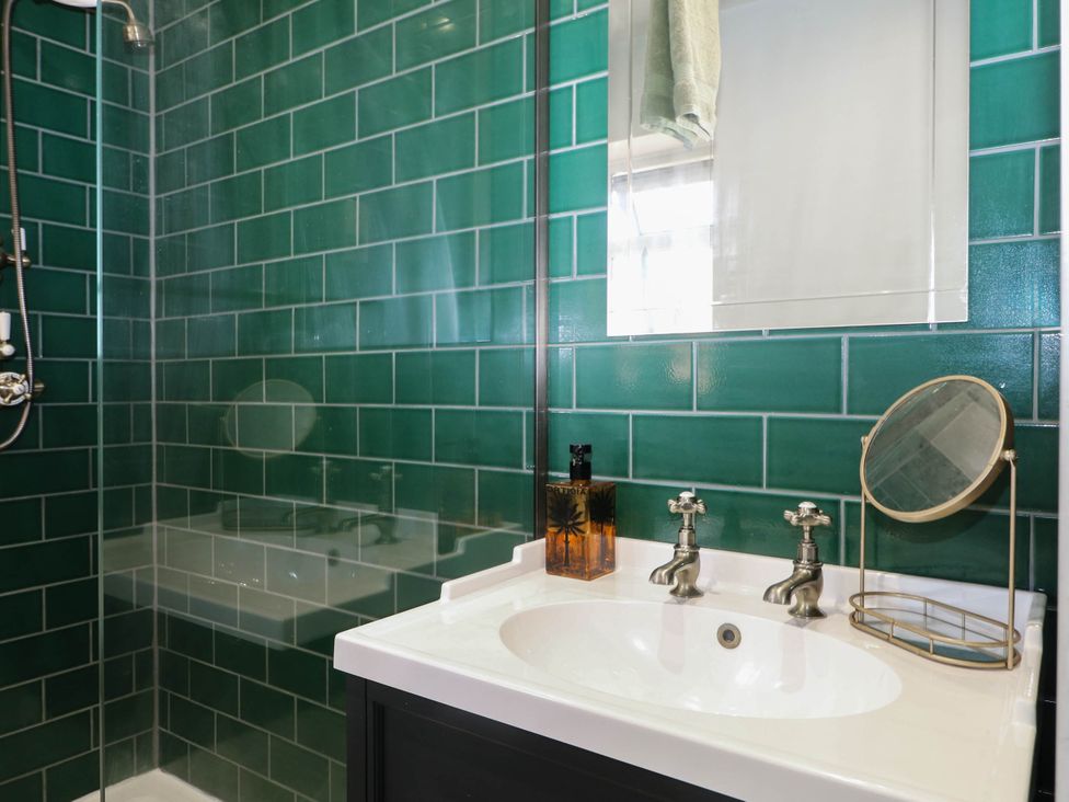 A bathroom with a shower, sink, and mirror at Taliesin in Hailsham