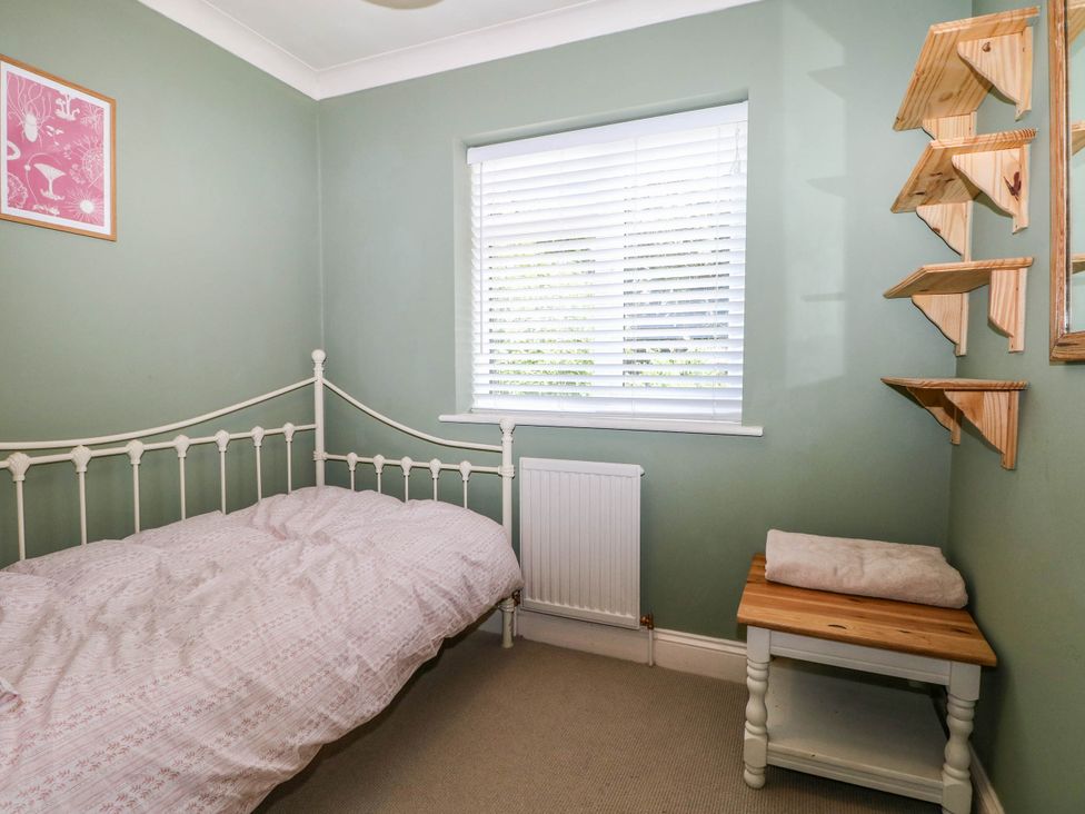 A bedroom with a bed and shelves at Taliesin in Hailsham