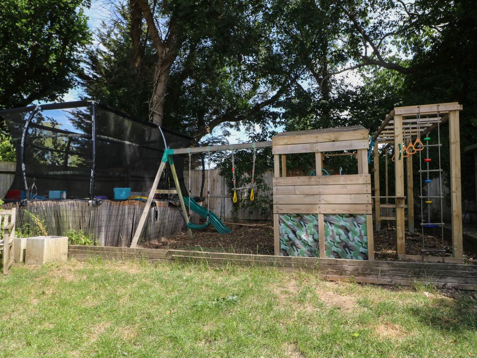 A garden with a trampoline and a playset at Taliesin Hailsham