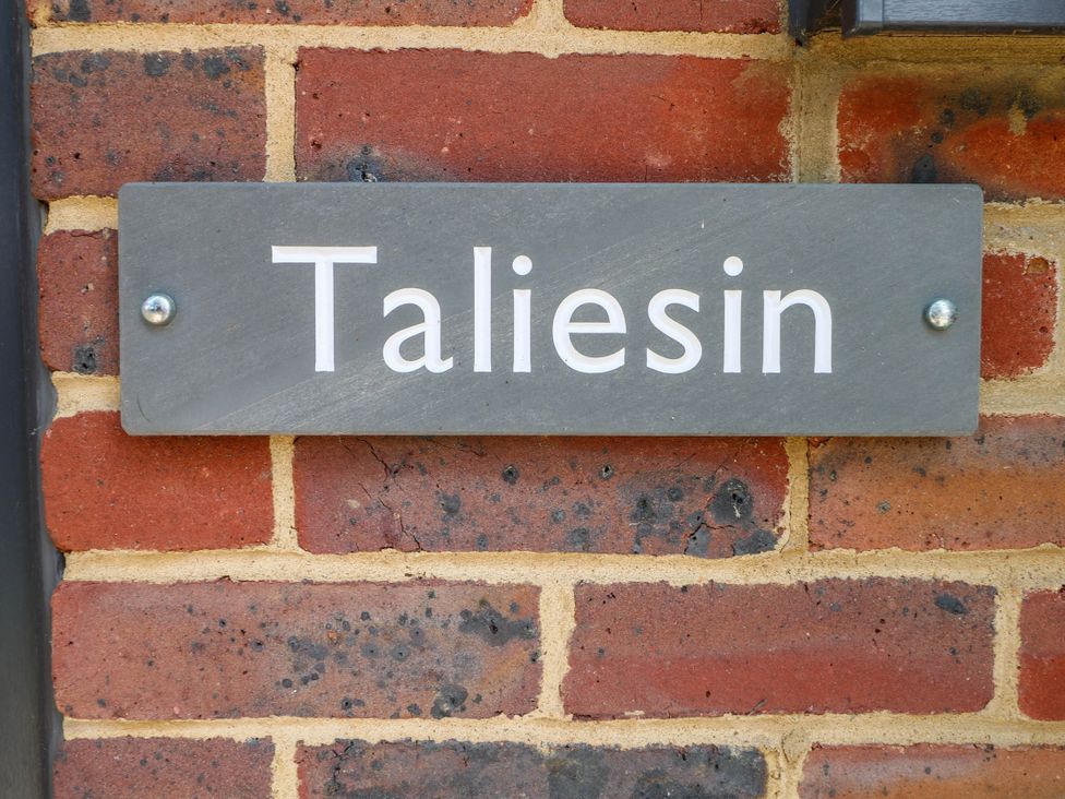 A sign with the name Taliesin on a brick wall