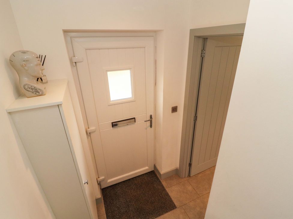 A hallway with a front door and cupboard at 11 The Forge in Brampton