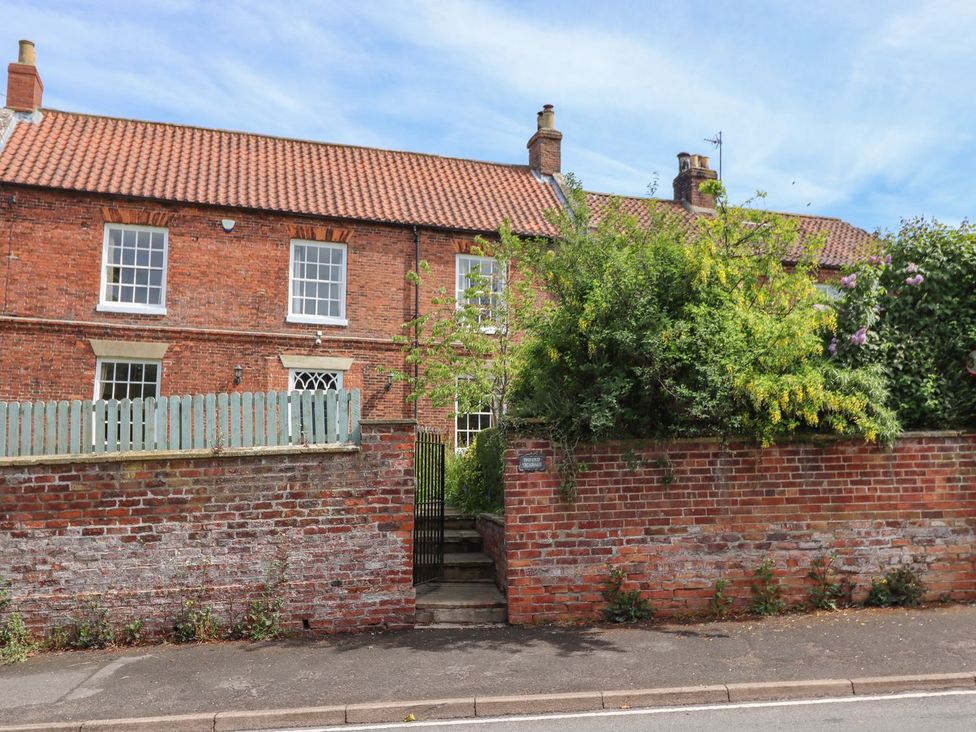 A brick house with windows and a gate at Reighton House in Filey