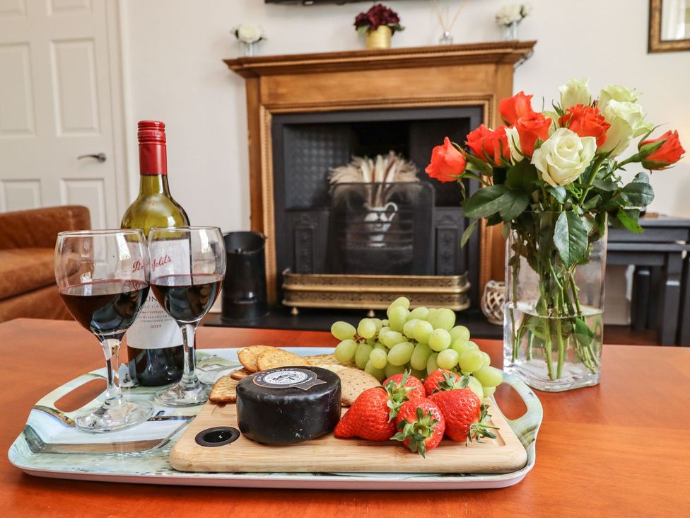 A living room with red wine, cheese, strawberries, and roses at Reighton House in Filey