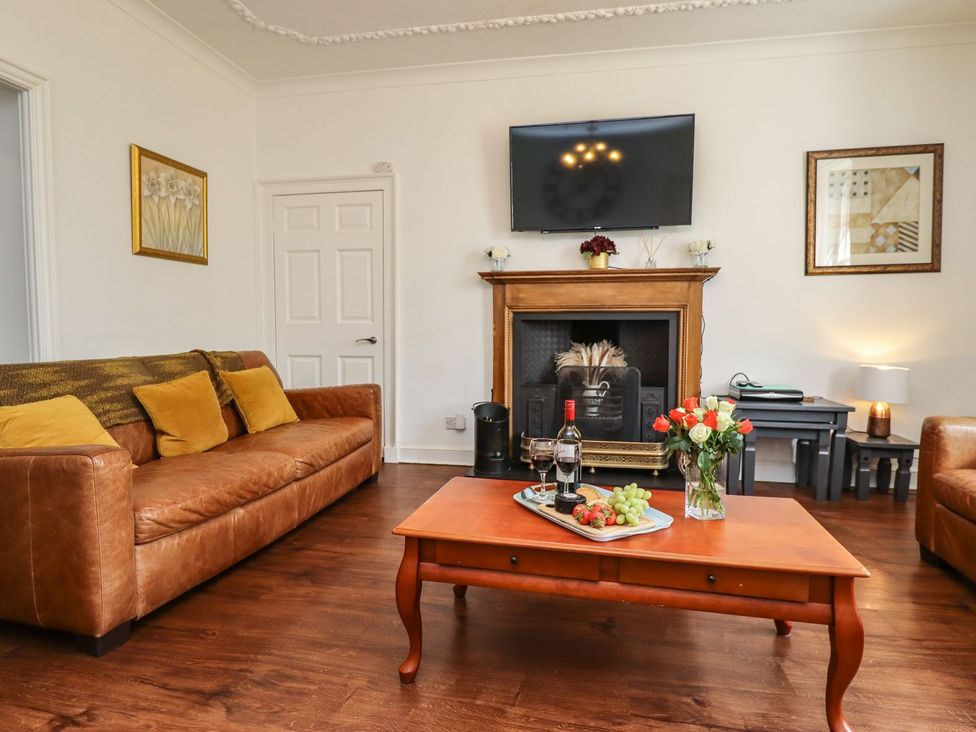 A living room with a sofa, television, and fireplace at Reighton House in Filey