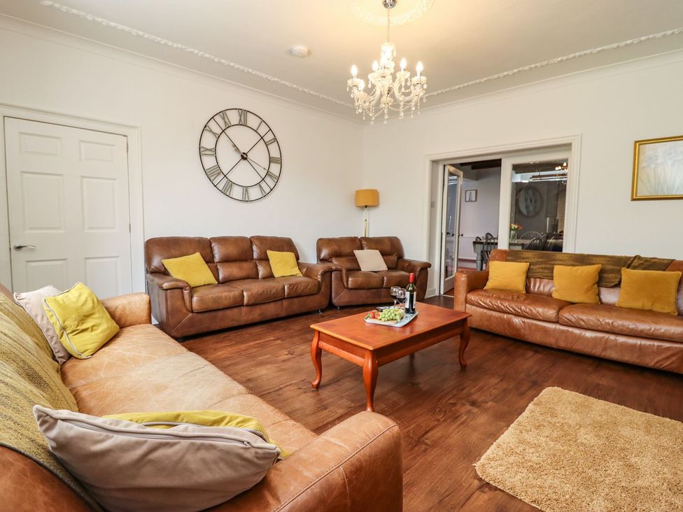 A living room with a sofa, coffee table, and clock at Reighton House in Filey