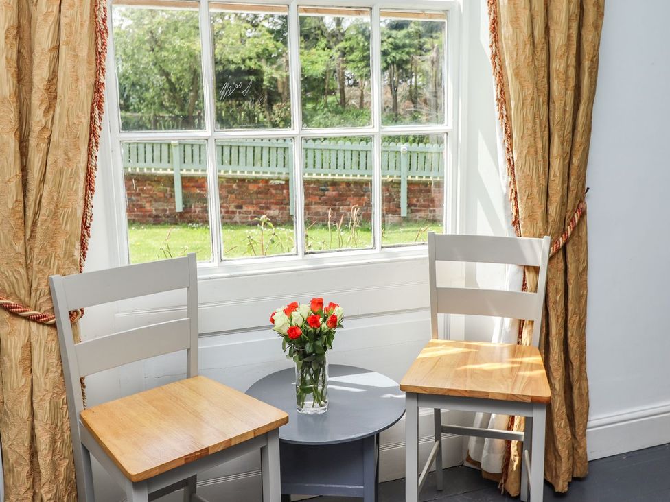 A sitting room with two chairs and a table near a window at Reighton House in Filey