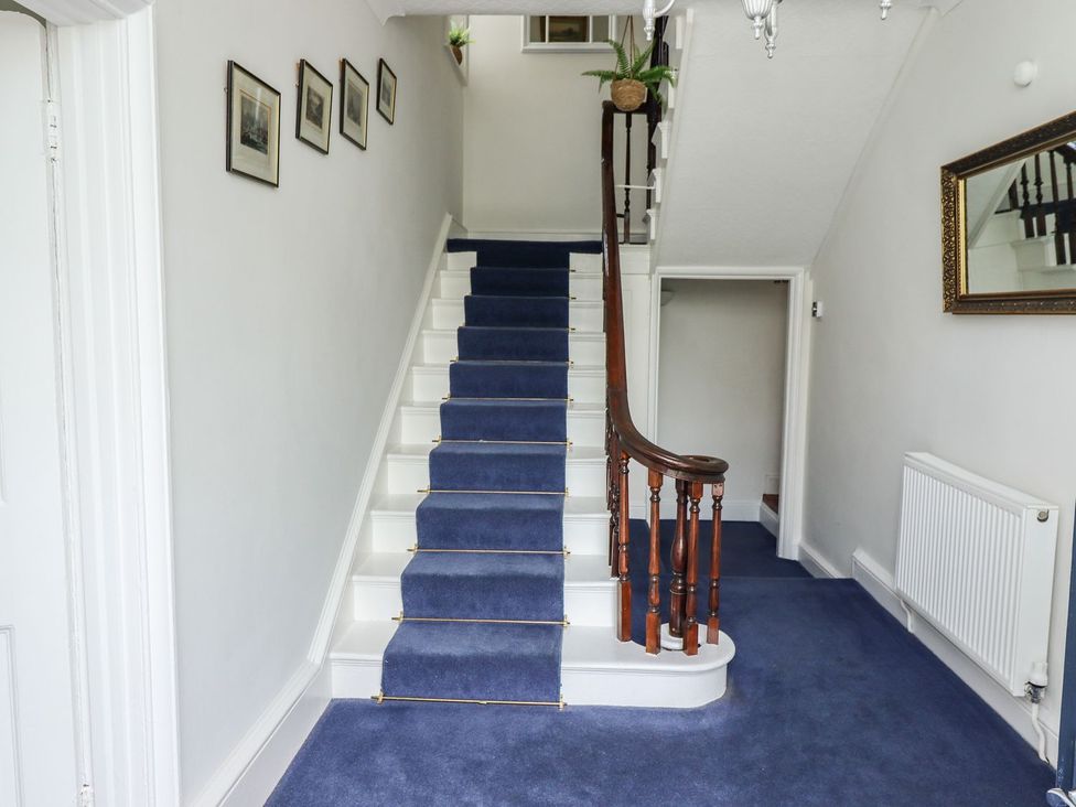 A hallway with stairs and a mirror at Reighton House in Filey