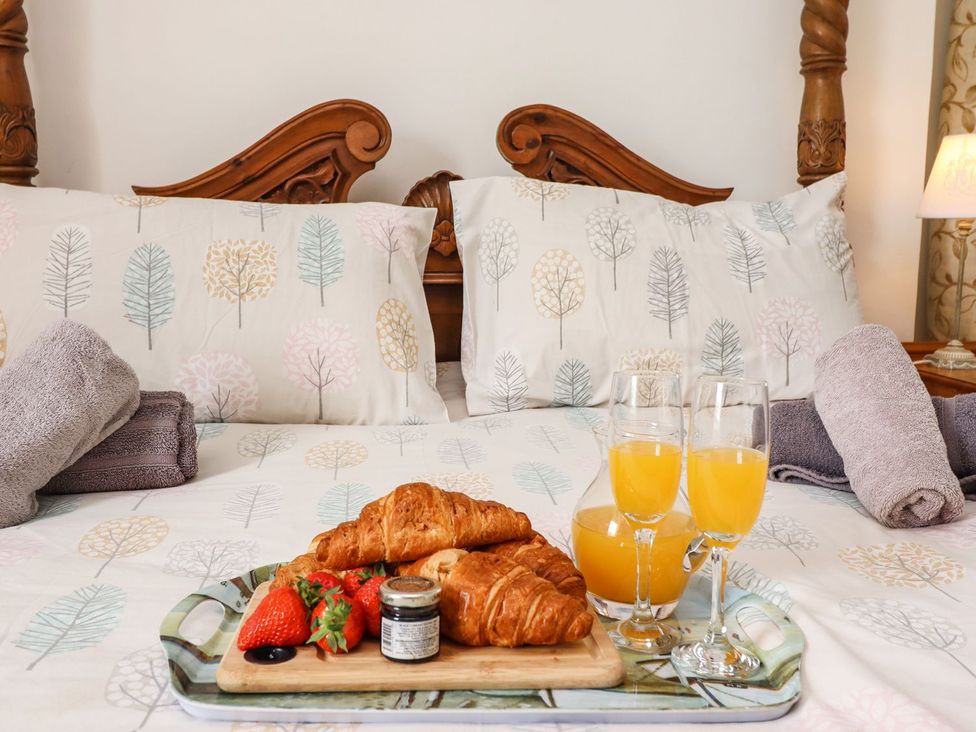 A breakfast tray with croissants, strawberries, and juice on a bed at Reighton House in Filey