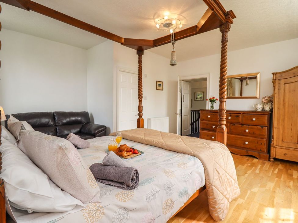 A bedroom with a four-poster bed and a couch at Reighton House in Filey