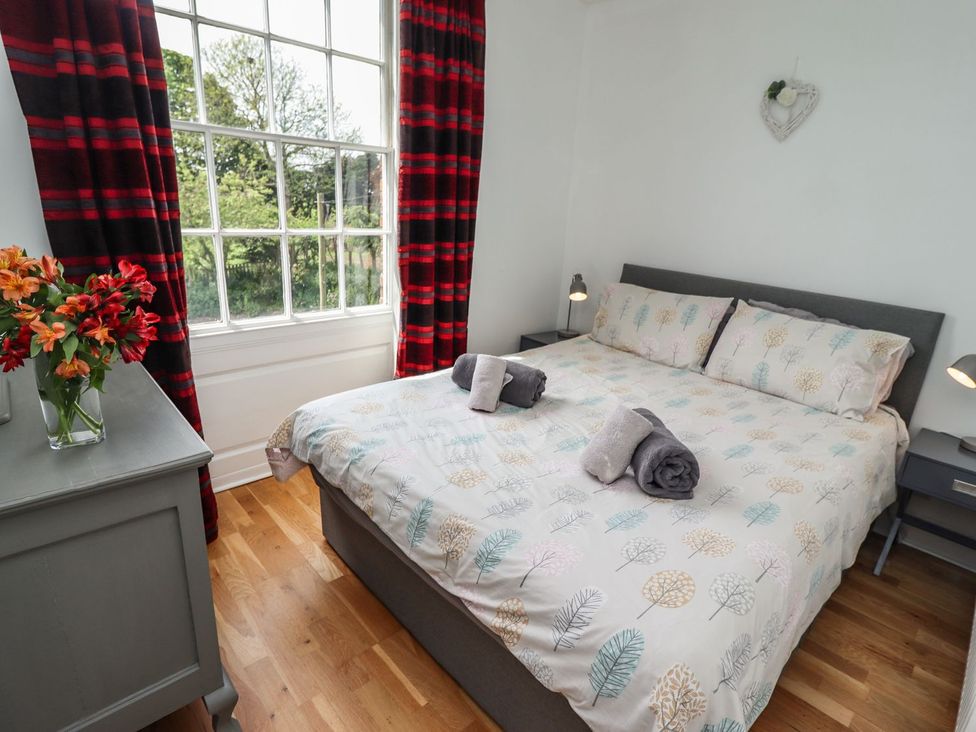 A bedroom with a bed, bedside tables, and a window at Reighton House in Filey