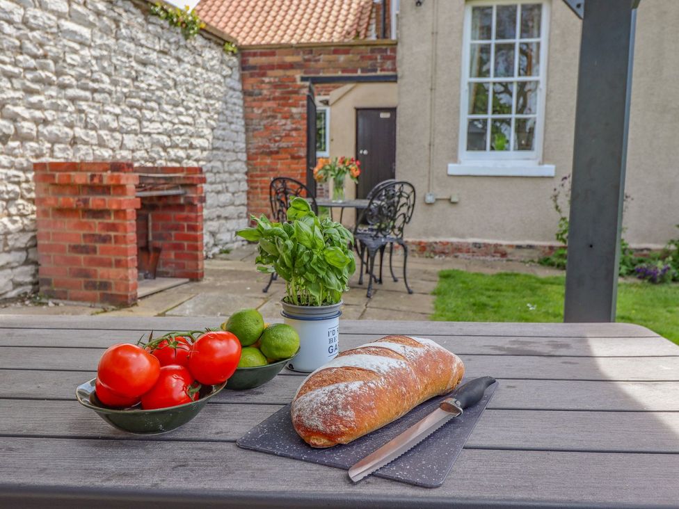 An outdoor dining area with bread, tomatoes, limes, and basil at Reighton House in Filey