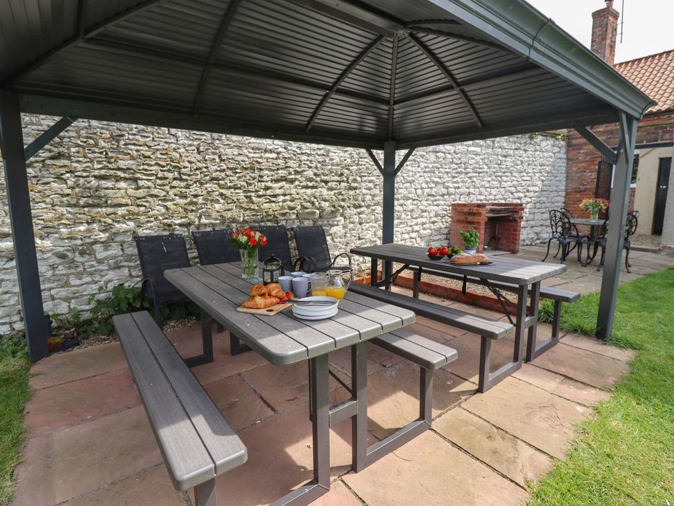 An outdoor dining area with a table and benches at Reighton House in Filey