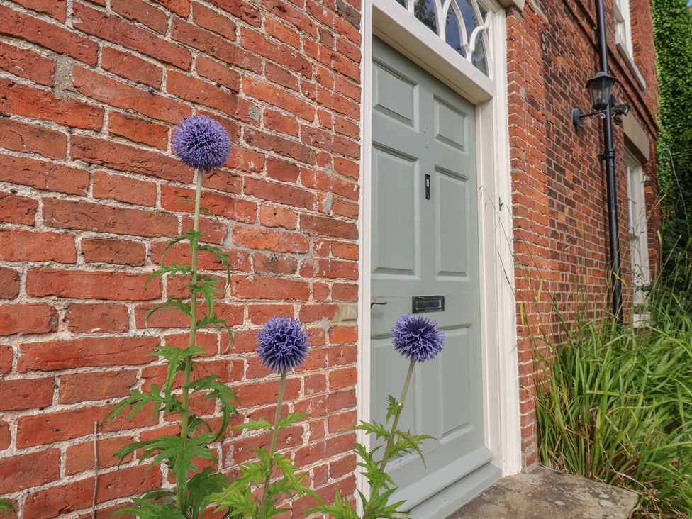 An entrance door with flowers in front of a brick wall at Reighton House Reighton near Filey