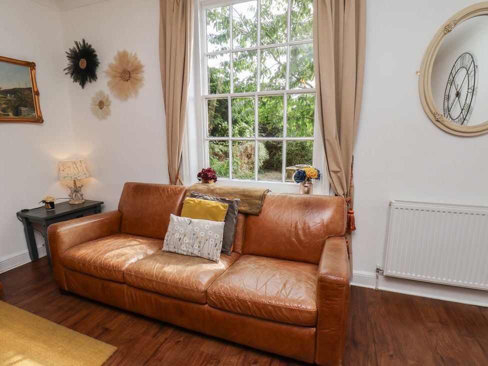 A living room with a sofa and lamp at Reighton House in Reighton near Filey