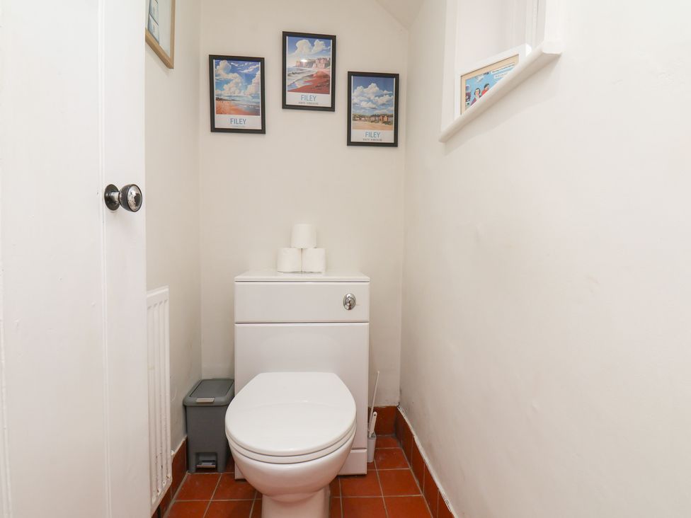 A bathroom with a toilet and pictures on the wall at Reighton House Reighton near Filey