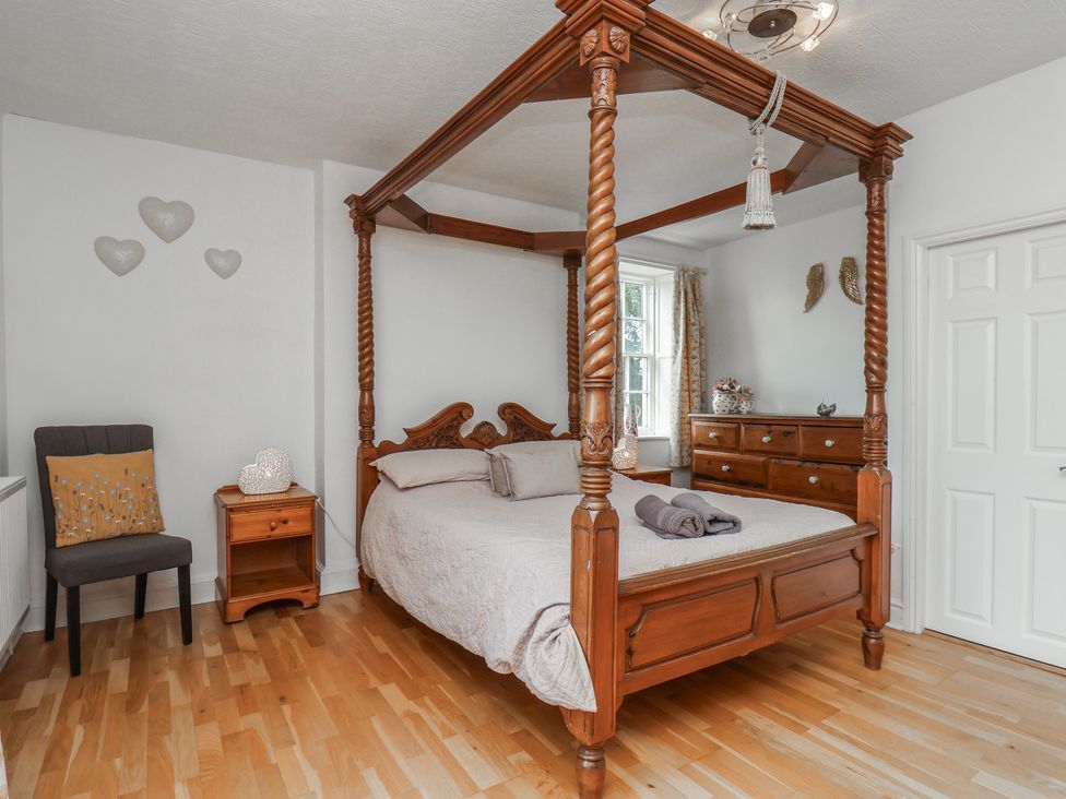 A bedroom with a four-poster bed and a dresser at Reighton House in Reighton near Filey