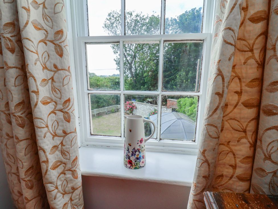 A window with curtains and a flower vase at Reighton House Reighton near Filey