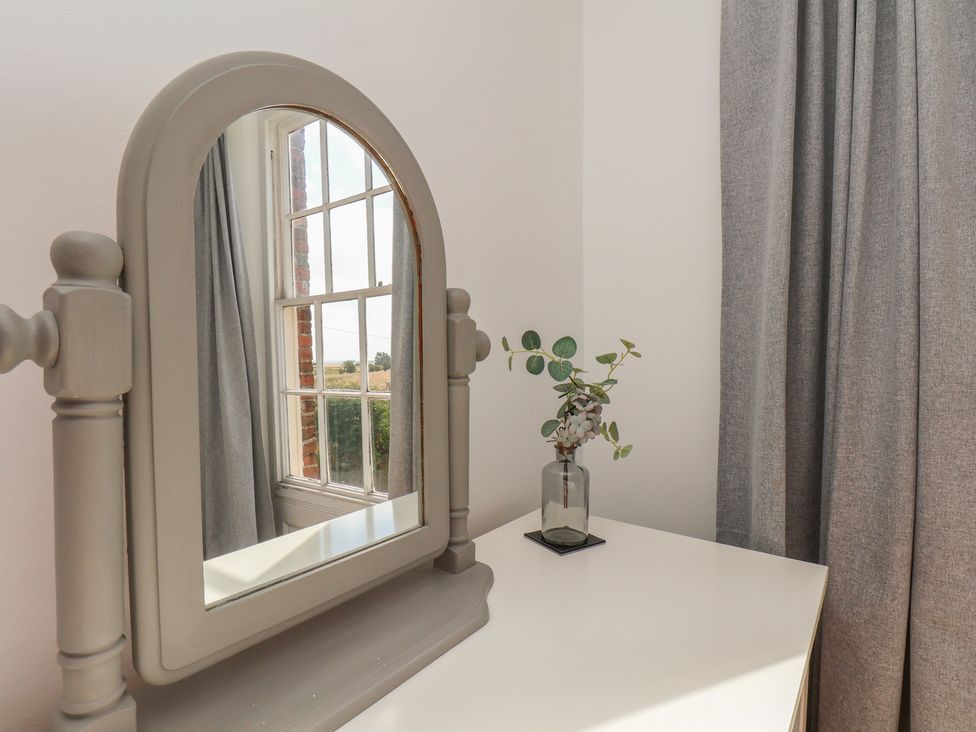 A mirror and plant on a table in a bedroom at Reighton House Reighton near Filey