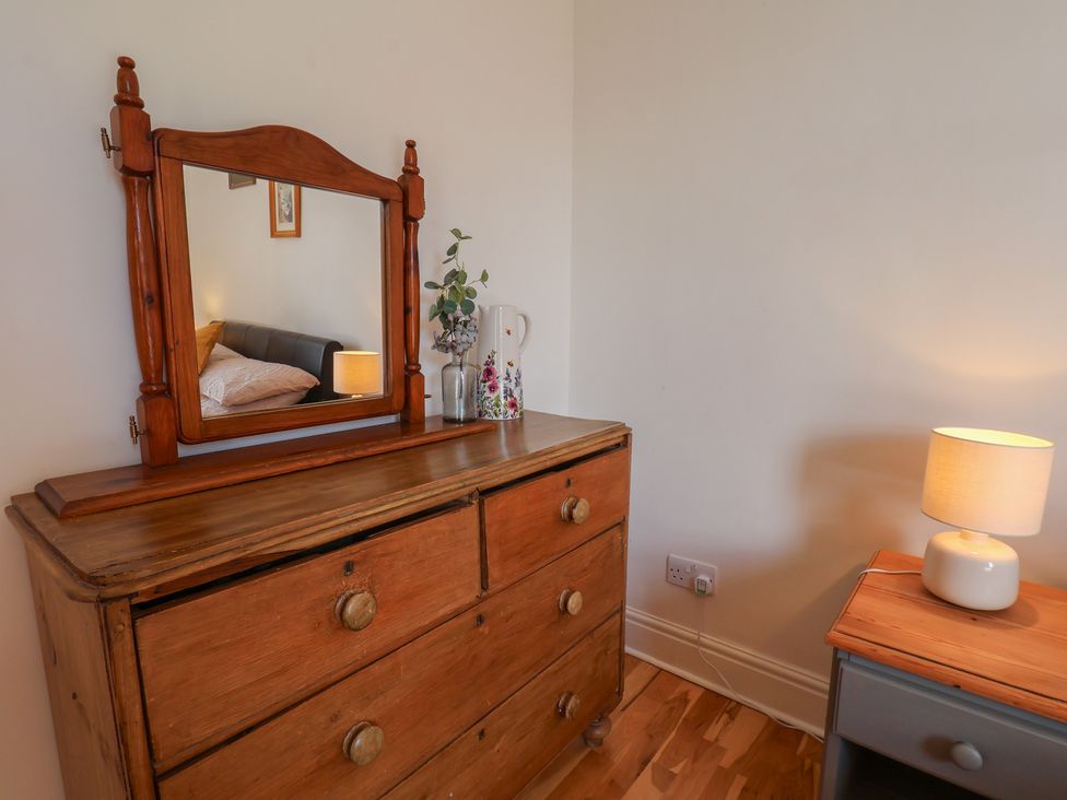 A bedroom with a dresser and mirror at Reighton House near Filey