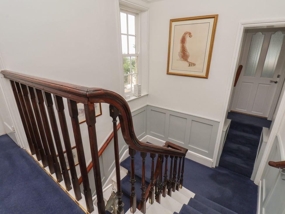 A staircase with a handrail and wall art at Reighton House in Reighton near Filey