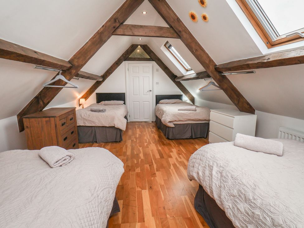 A bedroom with three beds and wooden beams at Reighton House in Reighton near Filey