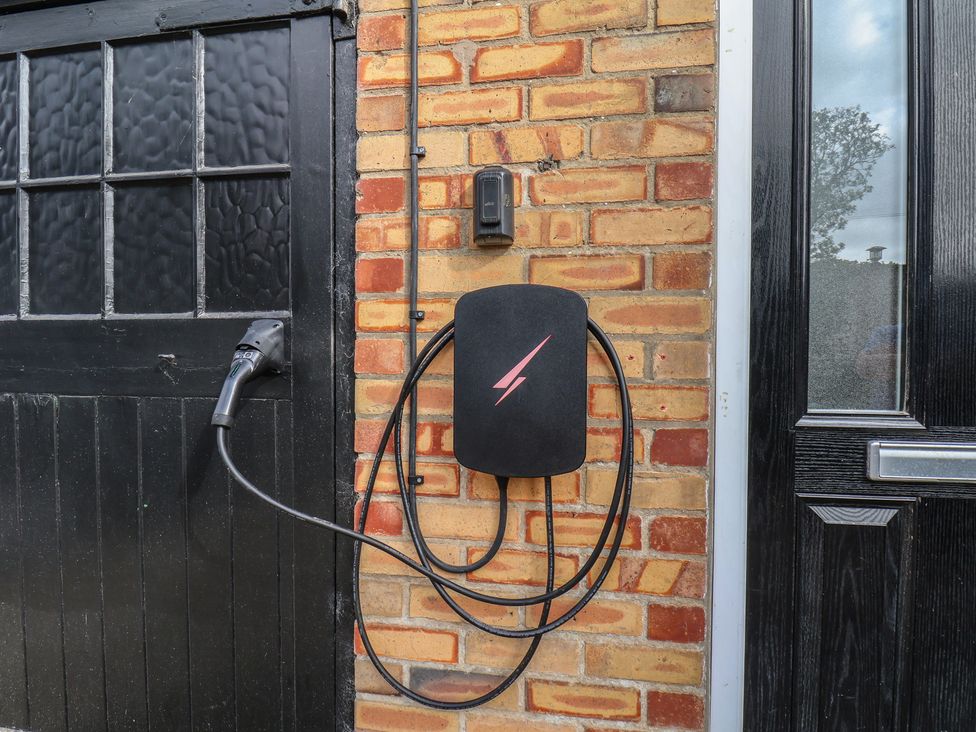 An electric vehicle charger on a brick wall at Reighton House near Filey