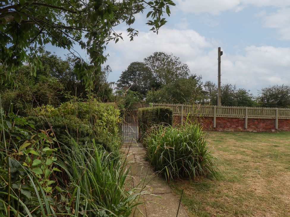 A garden with a pathway leading to a gate at Reighton House in Reighton near Filey
