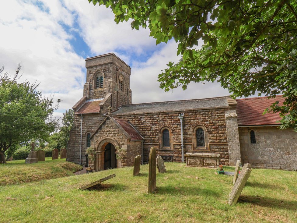 A church with a tower and gravestones at Reighton House in Reighton near Filey
