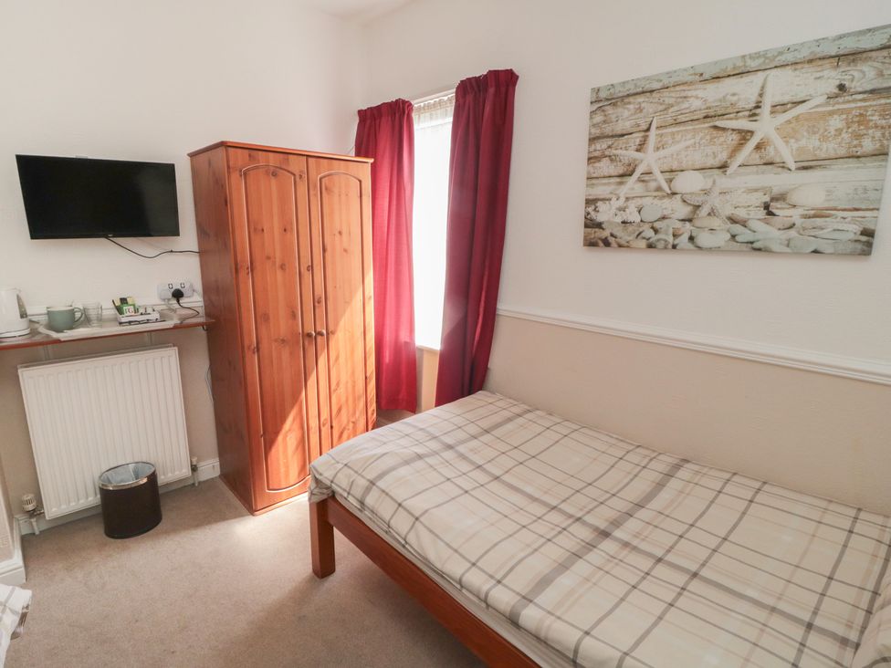A bedroom with a bed and wardrobe at Meltham Guest House in Scarborough