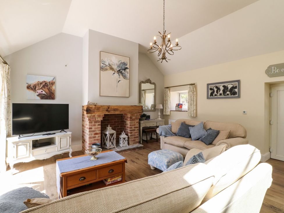 A living room with a fireplace and television at Churn Dash Cottage in Derby