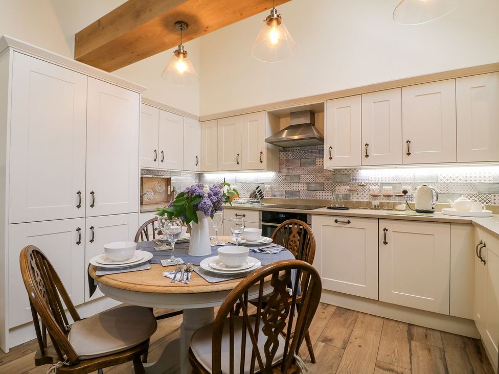 A kitchen with a dining table and chairs at Churn Dash Cottage Derby