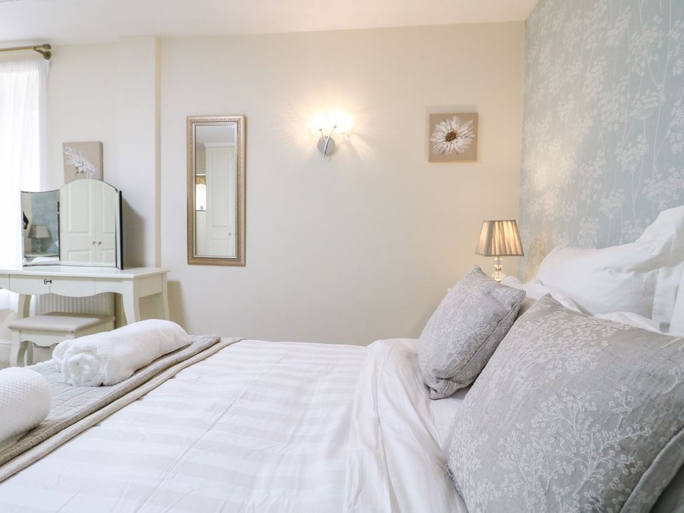 A bedroom with a bed and dressing table at Churn Dash Cottage in Derby