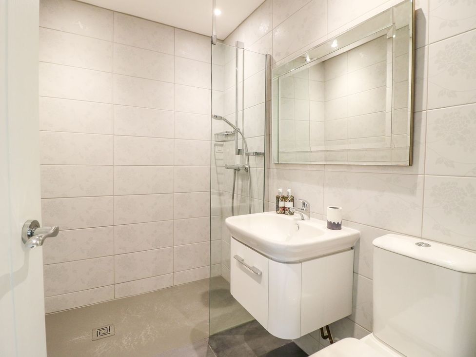A bathroom with a shower, sink, and toilet at Churn Dash Cottage Derby