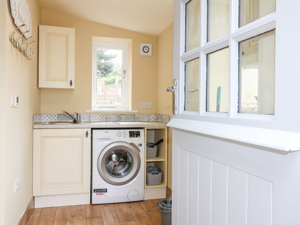 A laundry room with a washing machine and sink at Churn Dash Cottage Derby
