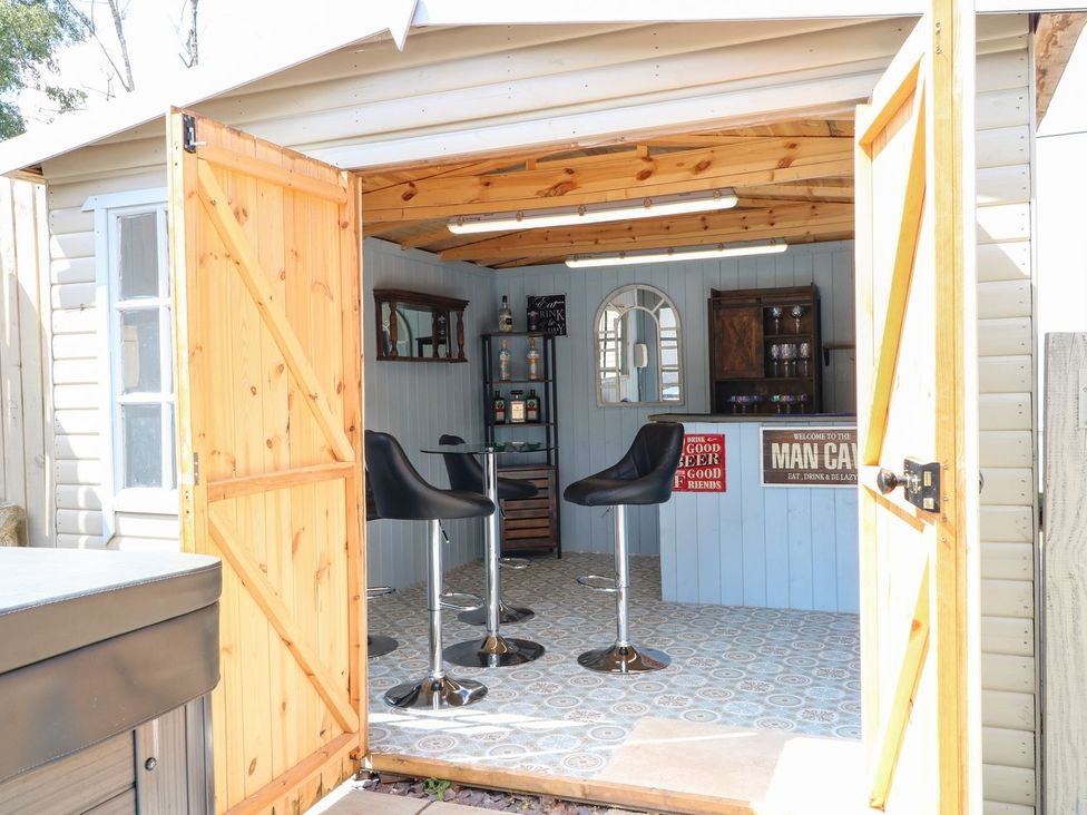 An outdoor bar with stools and shelves at Churn Dash Cottage in Derby