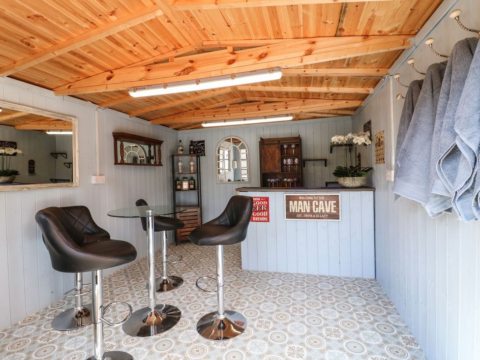 A bar area with stools and a mirror at Churn Dash Cottage Derby