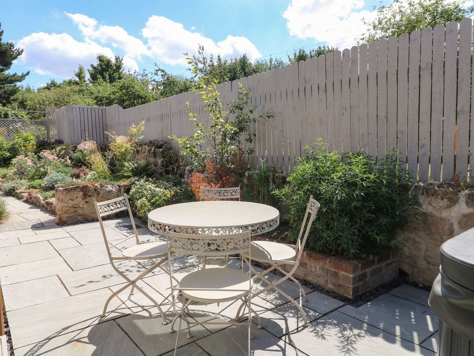 A garden with a table and chairs at Churn Dash Cottage in Derby
