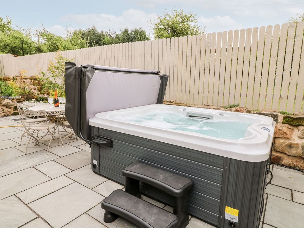 A hot tub with surrounding table and chairs at Churn Dash Cottage Derby