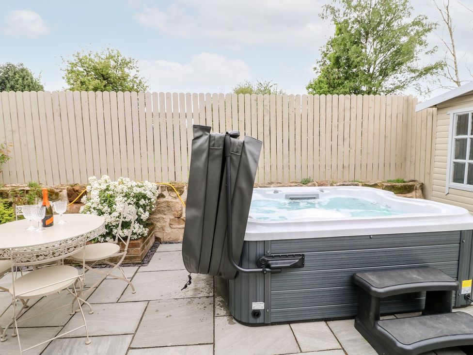 An outdoor area with a hot tub and a table with chairs at Churn Dash Cottage Derby