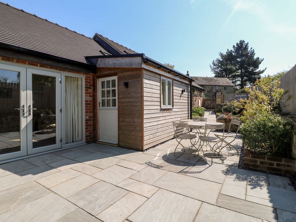 A patio area with a table and chairs at Churn Dash Cottage in Derby
