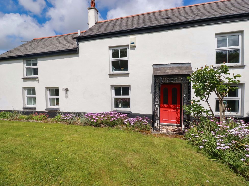 A house exterior with a red door and flower garden at Seveock in Threemilestone