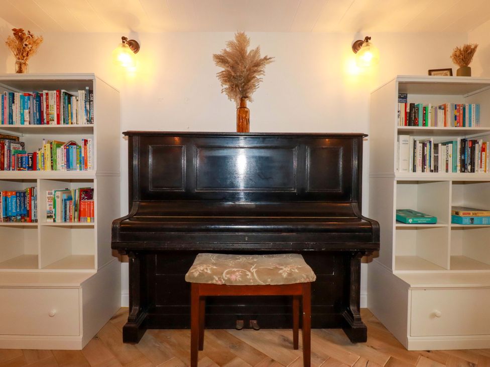 A living room with a piano and bookshelves at Seveock in Threemilestone