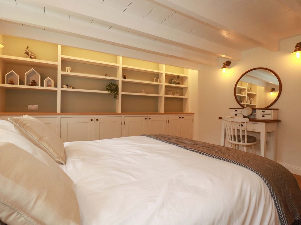 A bedroom with a bed and a desk with a mirror at Seveock in Threemilestone