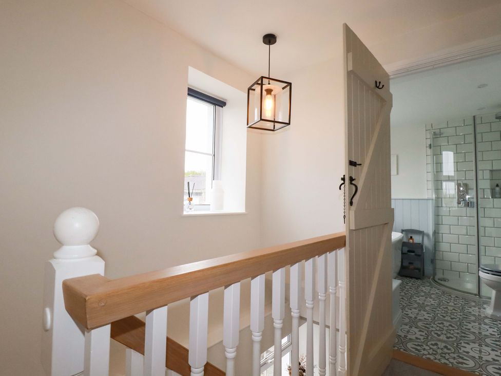 A hallway with a staircase and a bathroom entrance at Seveock in Threemilestone