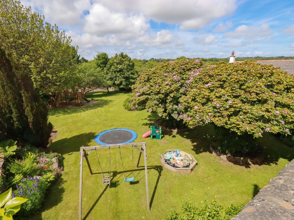 A garden with a trampoline and swing set at Seveock Threemilestone
